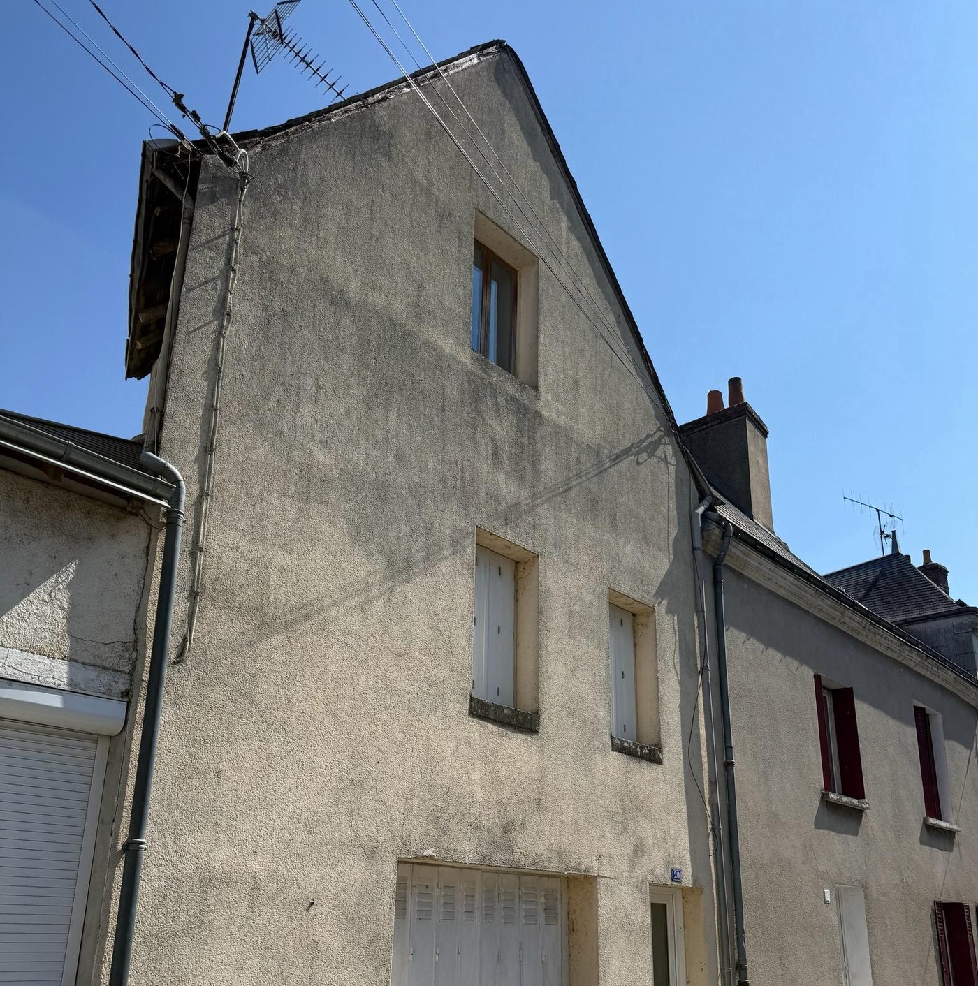 Le même pignon avant travaux : enduit taché par le ruissellement et débord de toit dégradé
